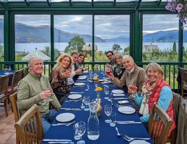 Group of hikers enjoying a meal together while overlooking a fjord and mountains