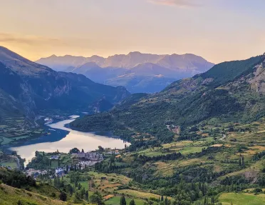 Wide shot of mountain valley town, river running through, sunset.