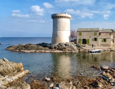 Shot of coastal inlet, wide watch tower, small houses seen.