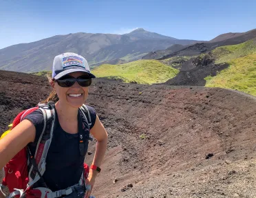 Guest taking selfie while standing in a small caldera. Mountains behind them.