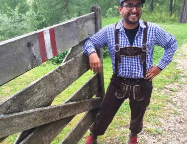 Local guide in traditional clothing posing for camera, leaning on wooden fence.