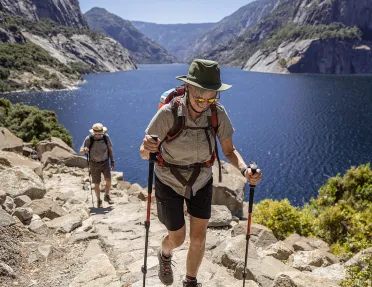 Two guests hiking beside large body of water.