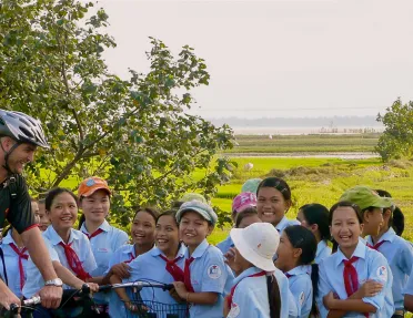 Backroads biker laughing with a group of children in Vietnam