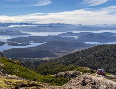 House on top of a mountain, with a valley of trees in the distance