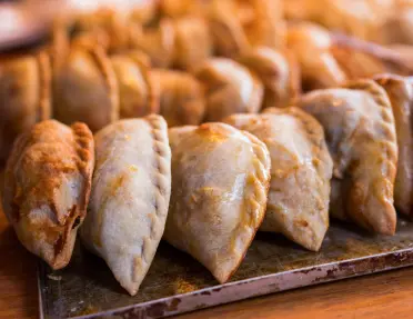 Empanadas lined up on a steel plate