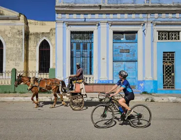 Woman riding a bike while looking at a man on a horse carriage