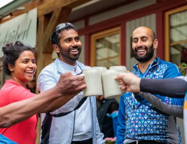 Group of people with beer steins clinking their mugs and laughing