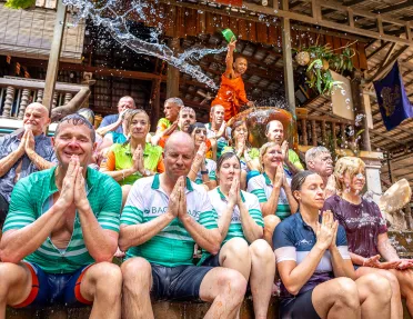 a group of people get splashed with water in a ceremony outside a temple