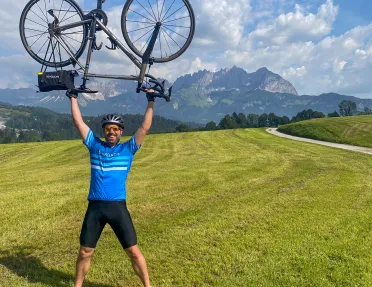 Man in a grassy field holding up a bike over his head