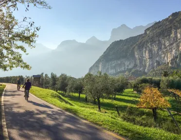 Two bikers on a road through grassy fields