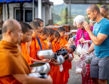 Group of people praying in front of monks with orange robes