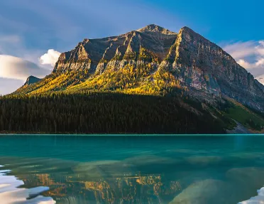 Mountain with tall trees behind a lake