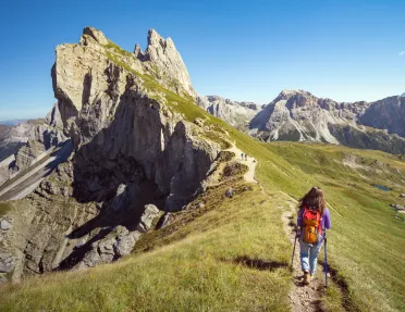Woman hiking on a dirt trail towards the edge of a cliff