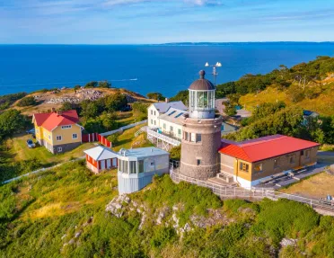 Lighthouse building with smaller buildings and the ocean in the distance