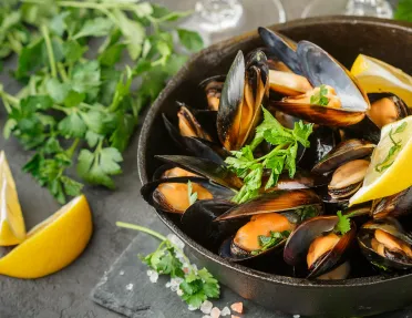 Bowel of cooked mussels with lemons and parsley