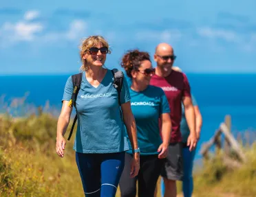Two women and one man walking on a trail