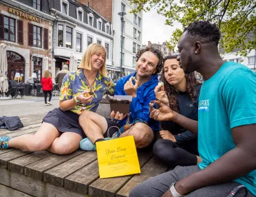 Two men and two women enjoy pastries on a bench