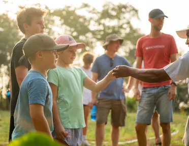 Man handing a flower to two kids