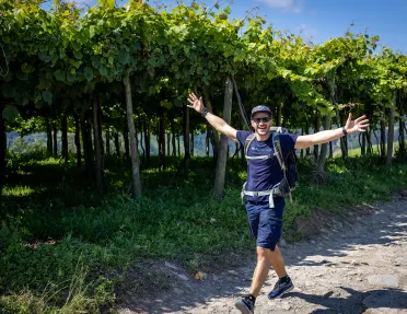 Man with arms wide open in front of vineyard