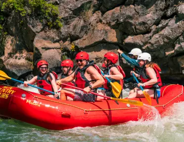 Group of people on a red raft, paddling through a river