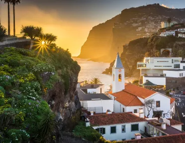 Sunset hitting a small town, filled with white and red buildings on cliffs