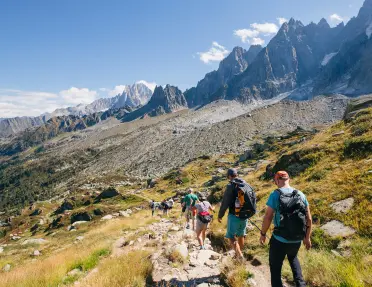 Group of hikers descending down a rocky and grassy hillside