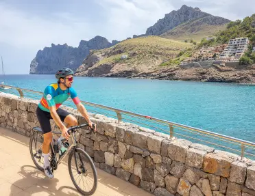Man biking on a stone path looking out to a lake and a small town