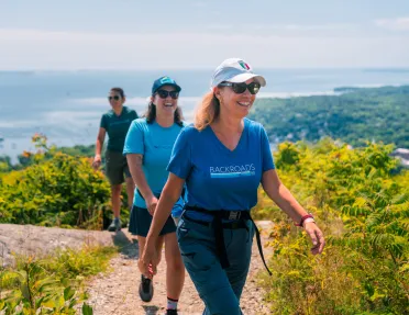 Three women smiling as they are hiking on a dirt trail
