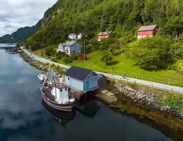a boat docked by a boathouse on a riverbank