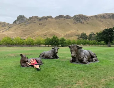 Woman laying down with statues of three cows