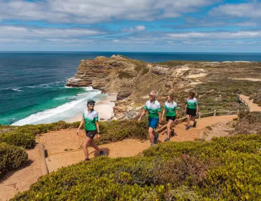 Four people hike up a sandy beach front road
