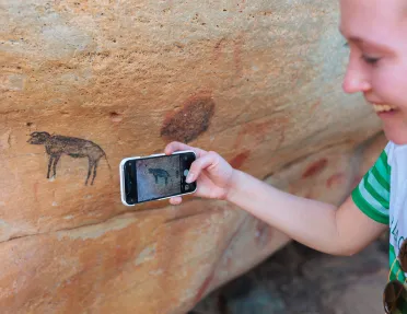 A person takes a photo of cave drawings