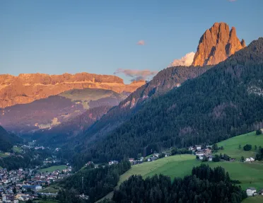 View of large hills covered in trees, with tall mountains in the distance