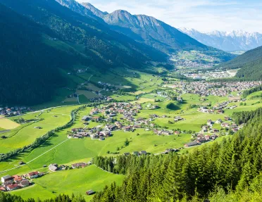 Small town scattered across a large grass valley, surrounded by large mountains