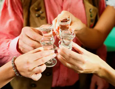 four shot glasses cheersing