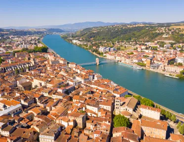 Brown and white buildings connected by a single bridge over a river