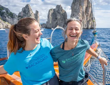 Two women on a boat, smiling while holding onto railings