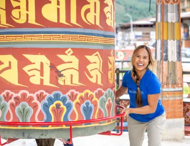 Woman smiling while holding a giant bell in a temple