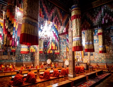 Monks sitting on the ground in the middle of a temply