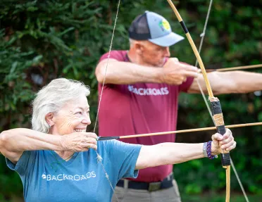 Man and woman smiling with holding a bow and arrow