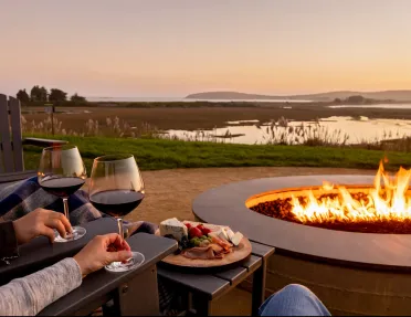 Outdoor fire pit with two glasses of wine and a charcuterie board 