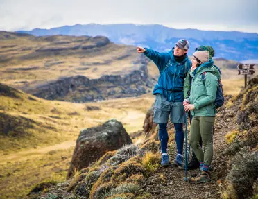 Man and two people pointing at an empty valley