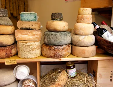 wheels of cheese stacked on a wooden counter