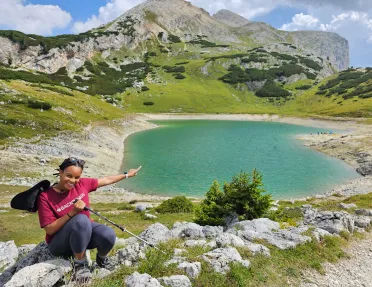 Woman sitting down and smiling, pointing at a small lake