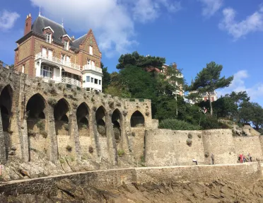Large house on top of stone castle ruins with a stone pathway on the ground level