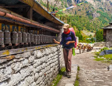 Woman walking along brick wall touching metal cans