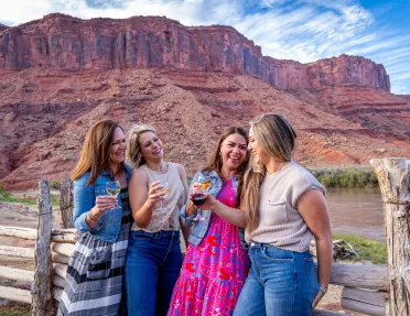 Four women holding wine glasses in front of canyons
