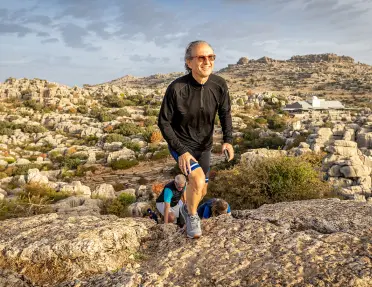 Man ascending a cliff with a large valley in the background