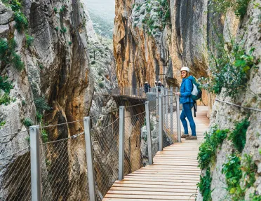 Woman standing on a wooden bridge, between two large cliffs