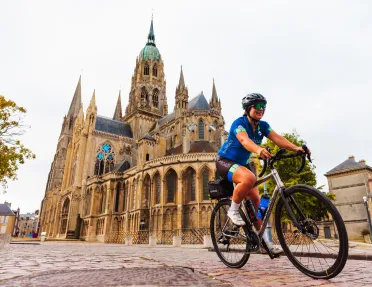 Woman riding a bike in front of a large cathedral with stained glass